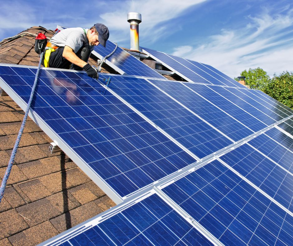 Instalador colocando placas solares fotovoltaicas en el tejado de una casa para generar energía renovable.