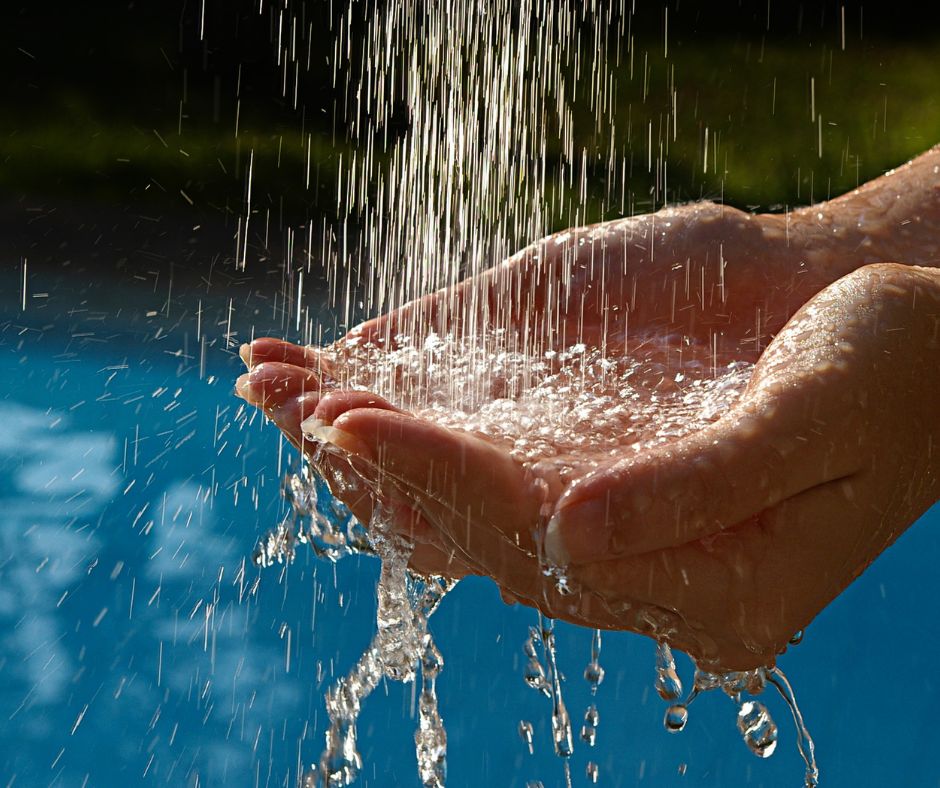 manos recogiendo agua caliente sanitaria bajo un chorro de agua, concepto de eficiencia energética con aerotermia